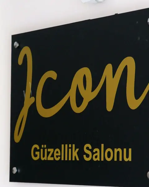 Salonun içindeki siyah zemin üzerine altın renkli Icon Güzellik Salonu tabelası